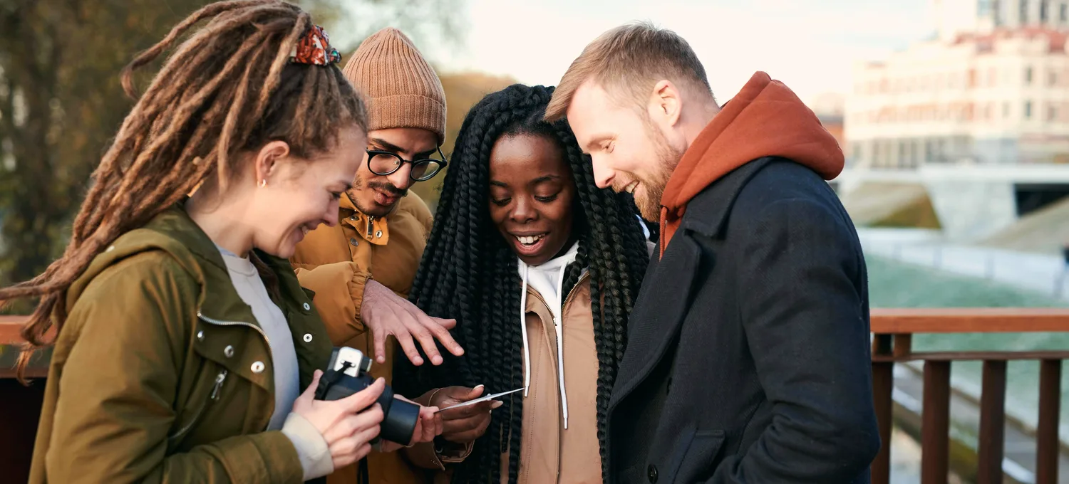 Friends gathered around a phone playing a mobile card game